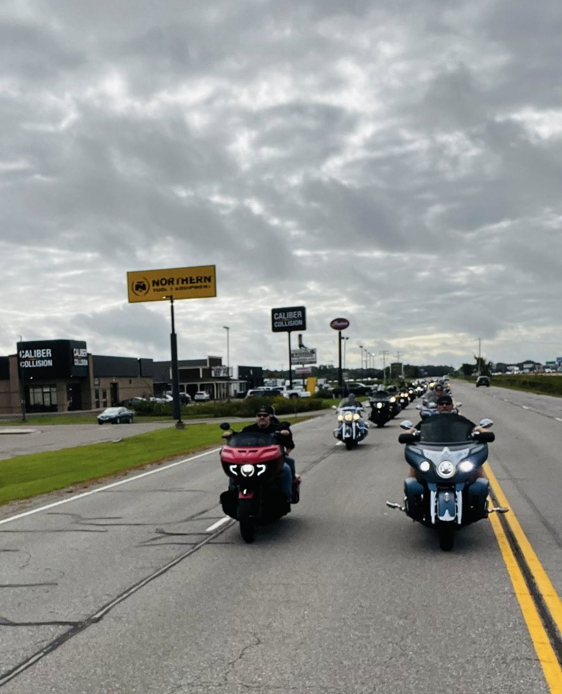 A long line of chapter riders on a highway under a cloudy sky