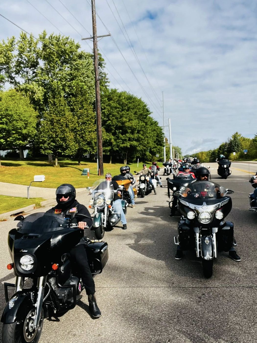 Chapter riders heading out together along a tree-lined road